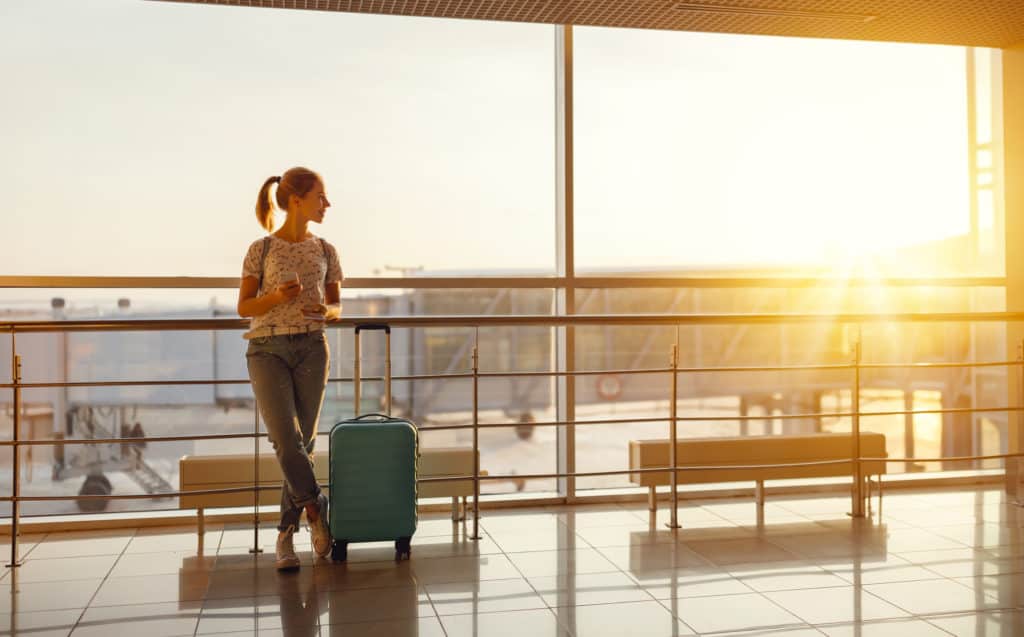 Young Woman Waiting at Airport with Suitcase